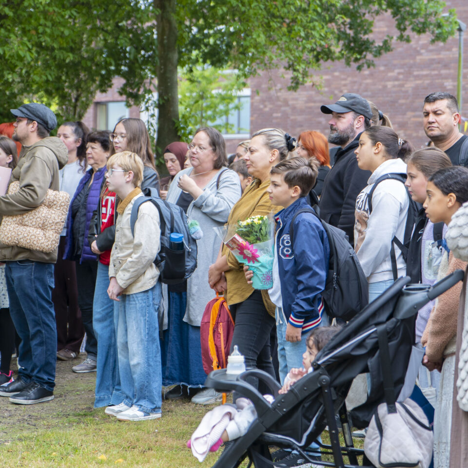 Neue Fünftklässler:innen und ihre Familien verfolgen gemeinsam die Einschulungsfeier auf dem Schulgelände.
