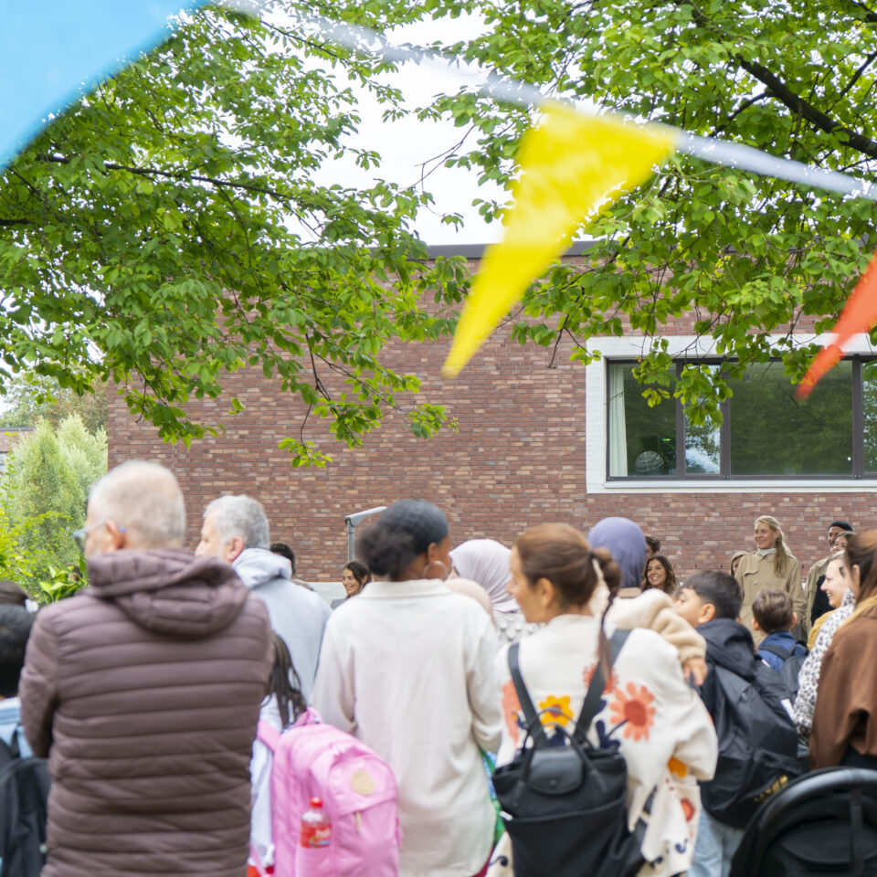 Zahlreiche Schüler:innen und Familien versammeln sich unter Bäumen zur Einschulungsfeier der neuen 5. Klassen.