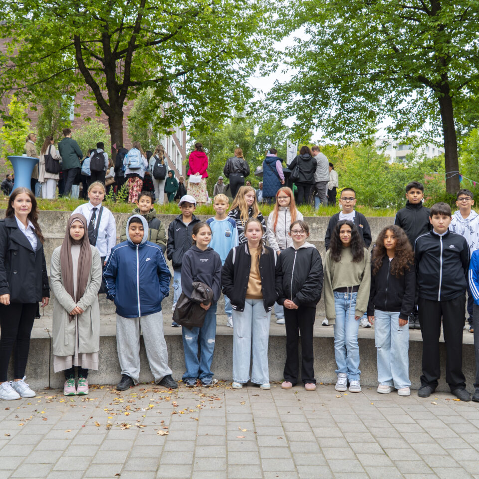 Die neue Klasse 5c steht gemeinsam mit ihrem Klassenteam für ein Gruppenfoto auf dem Schulgelände.