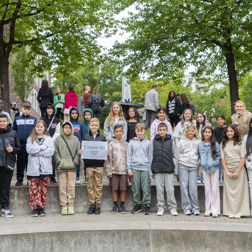 Die neue Klasse 5d steht gemeinsam mit ihrem Klassenteam für ein Gruppenfoto auf dem Schulgelände.