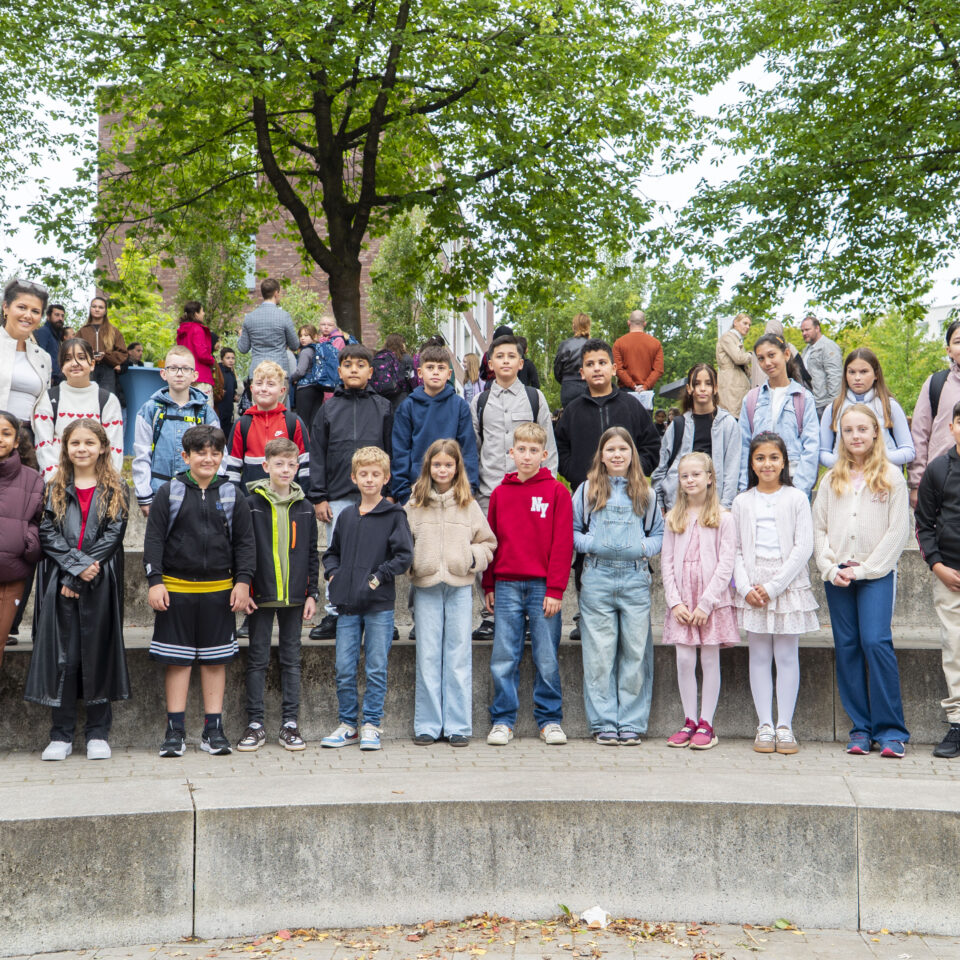Die neue Klasse 5e steht gemeinsam mit ihrem Klassenteam für ein Gruppenfoto auf dem Schulgelände.